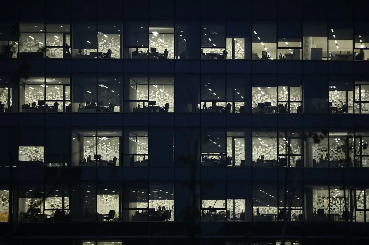 Étages de bureaux éclairés vus de nuit à travers une façade vitrée sombre