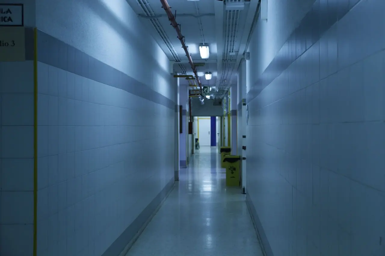 Couloir d'hôpital carrelé et faiblement éclairé, ambiance bleutée